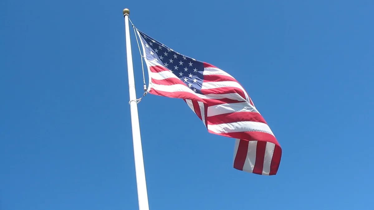 The flag of the United States waving in the wind against a clear blue sky